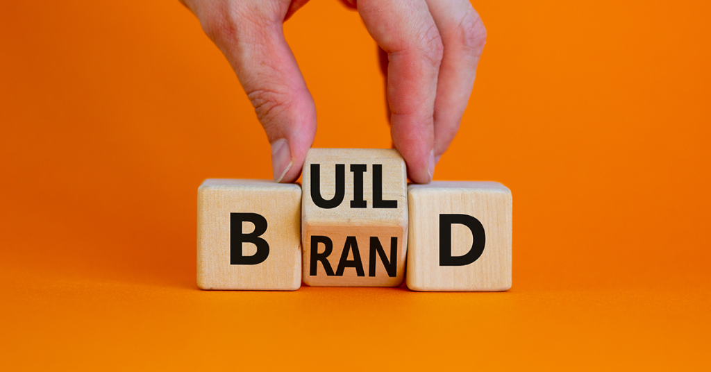 photo of a hand holding the middle of the word "Build" - made of three wooden blocks